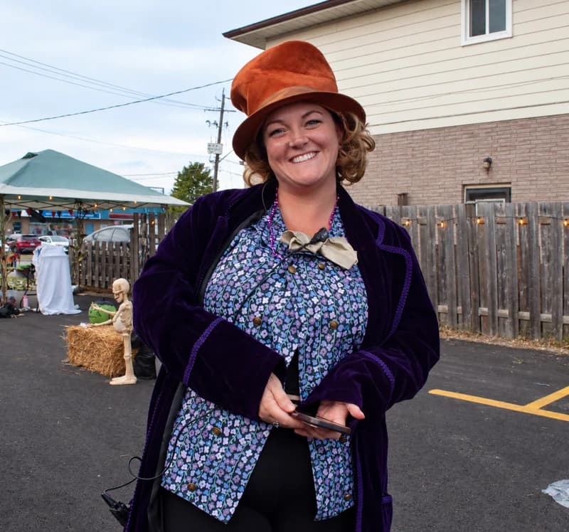 A smiling guest wears a copper top hat and purple velvet costume.